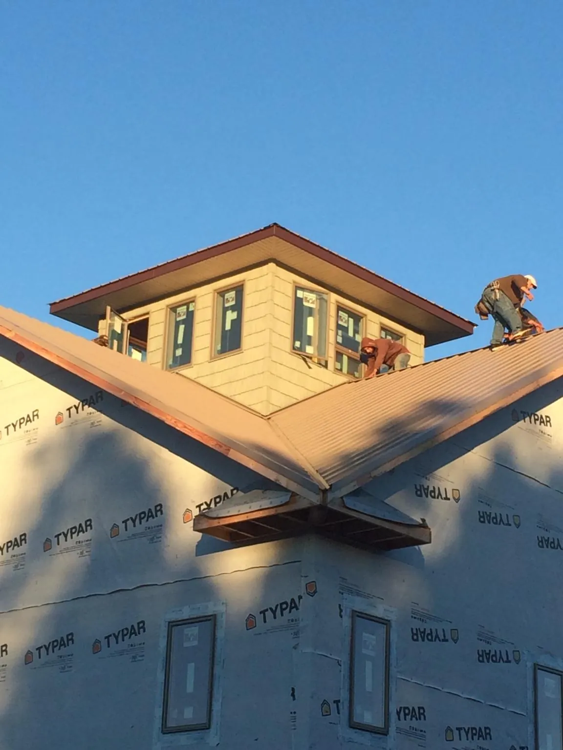 Roofers working around a rooftop cupola on a new metal roof at sunset — Roof Waterproofing in Pierson by Roofing Brothers